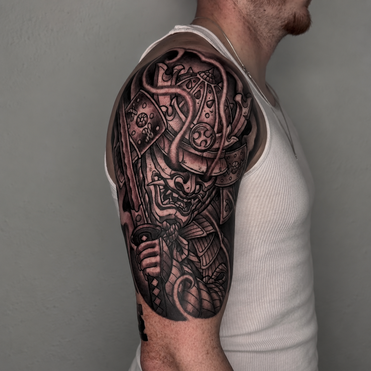Black and grey ornamental upper-arm tattoo by Adrian Aguirre.