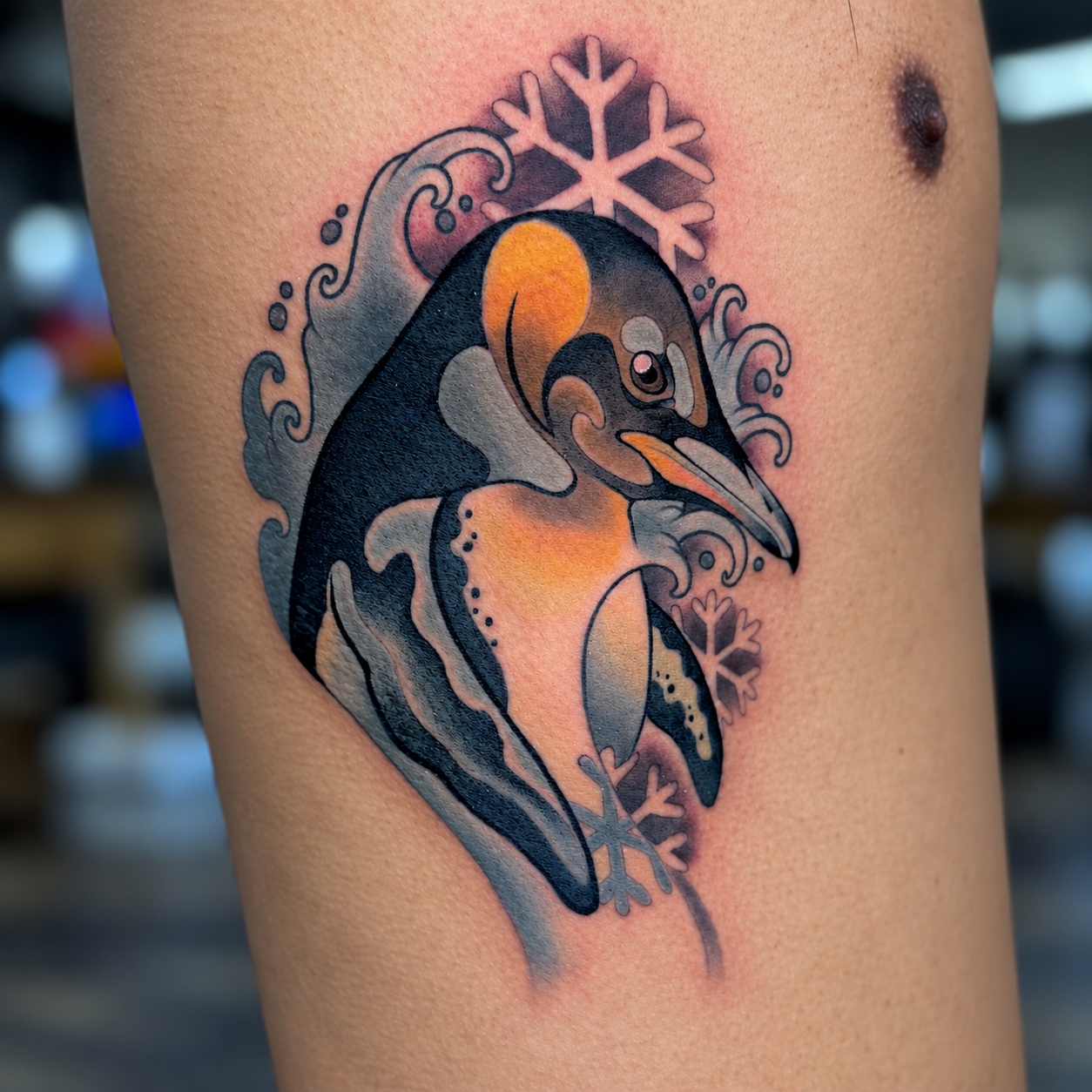 Color penguin tattoo with snowflake details by Adrian Aguirre.