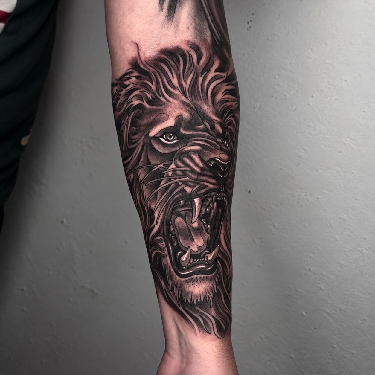 Black and grey roaring lion forearm tattoo by Adrian Aguirre.
