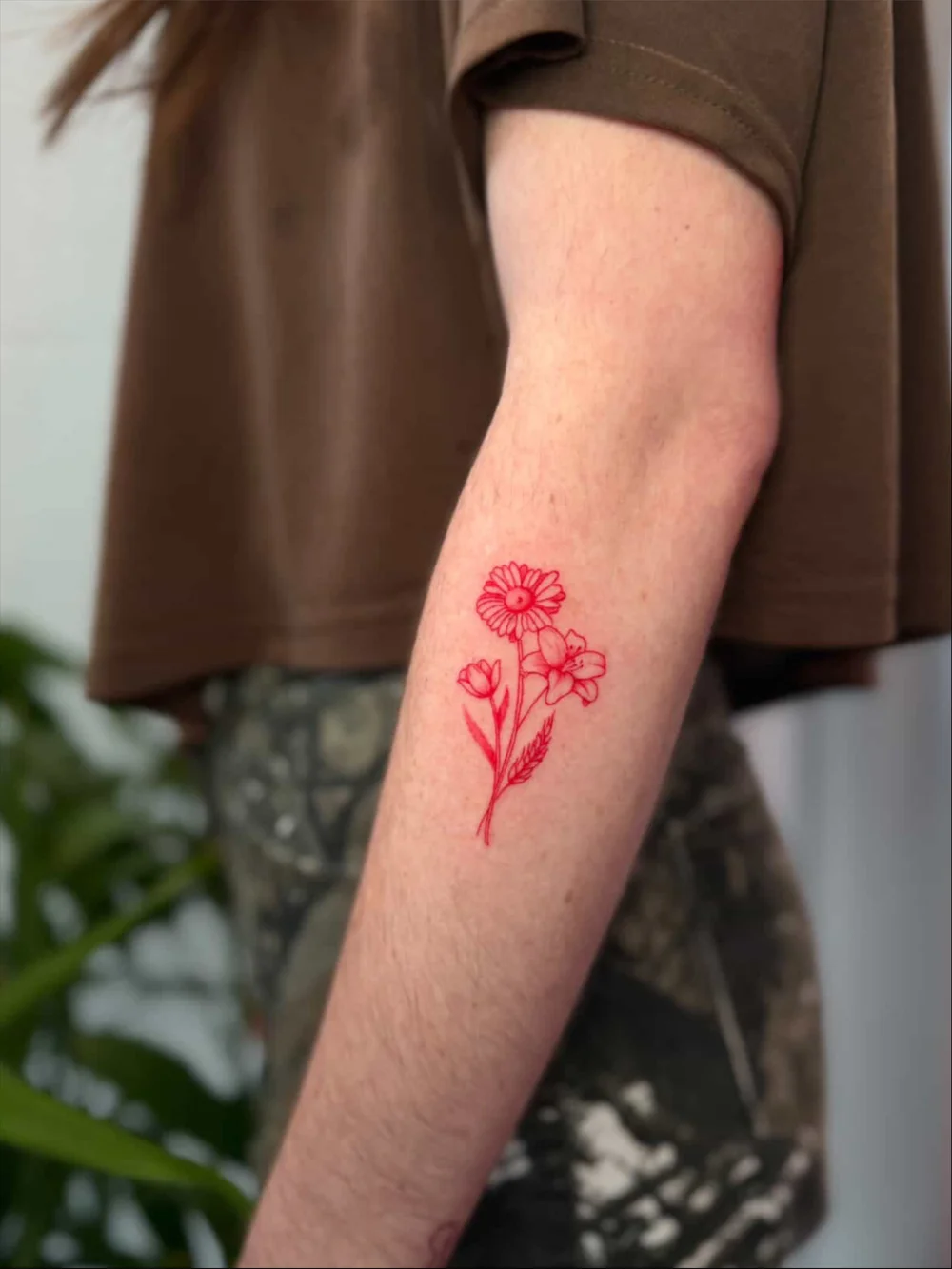 Minimalist fine line red floral tattoo on the forearm featuring delicate flowers and botanical details, created by Sandy at Black Nova Tattoo Collective in Miami.