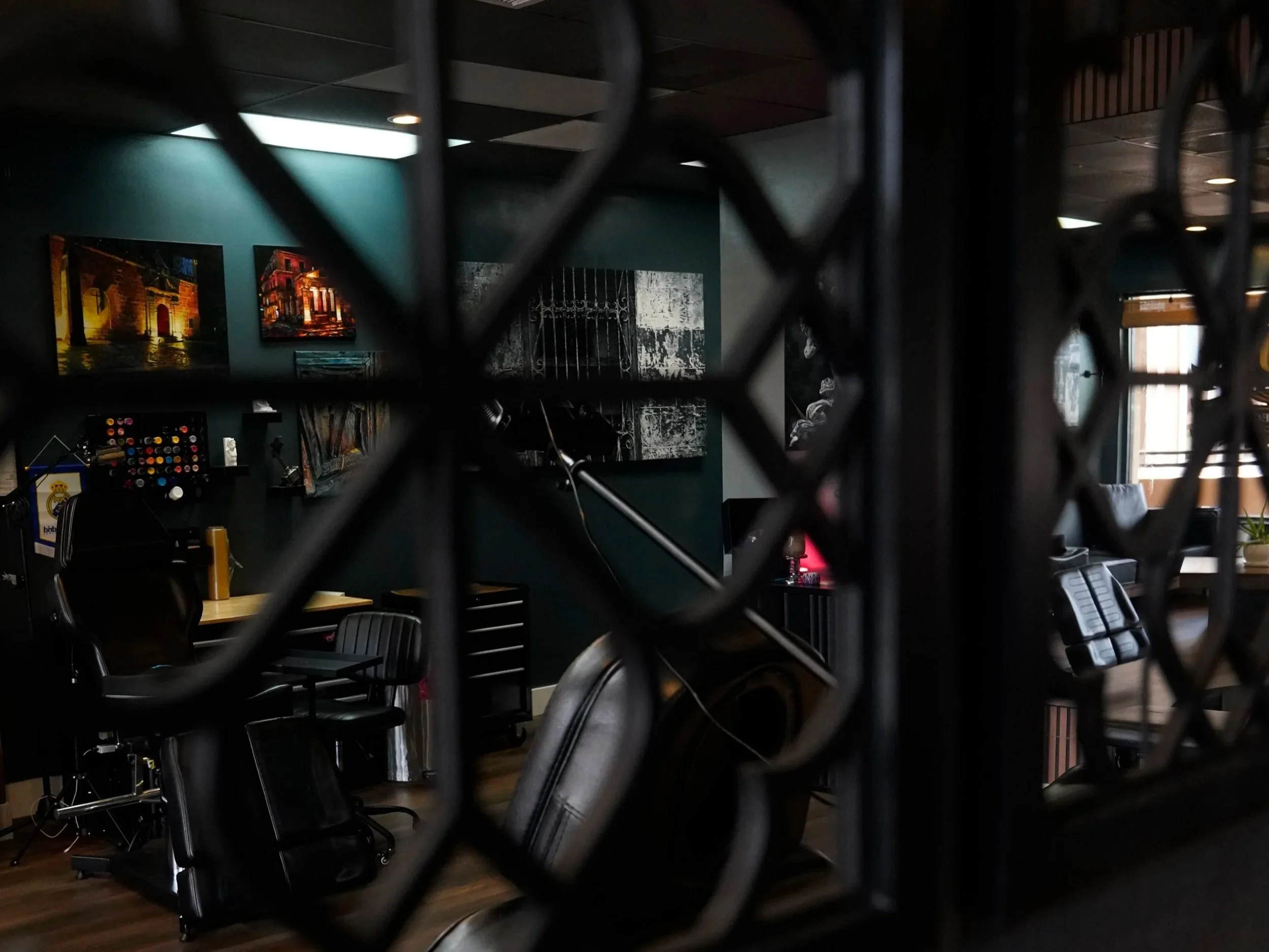 View into the Black Nova Tattoo Collective studio in Miami through decorative metalwork, showcasing tattoo stations, artwork, and a modern professional workspace.