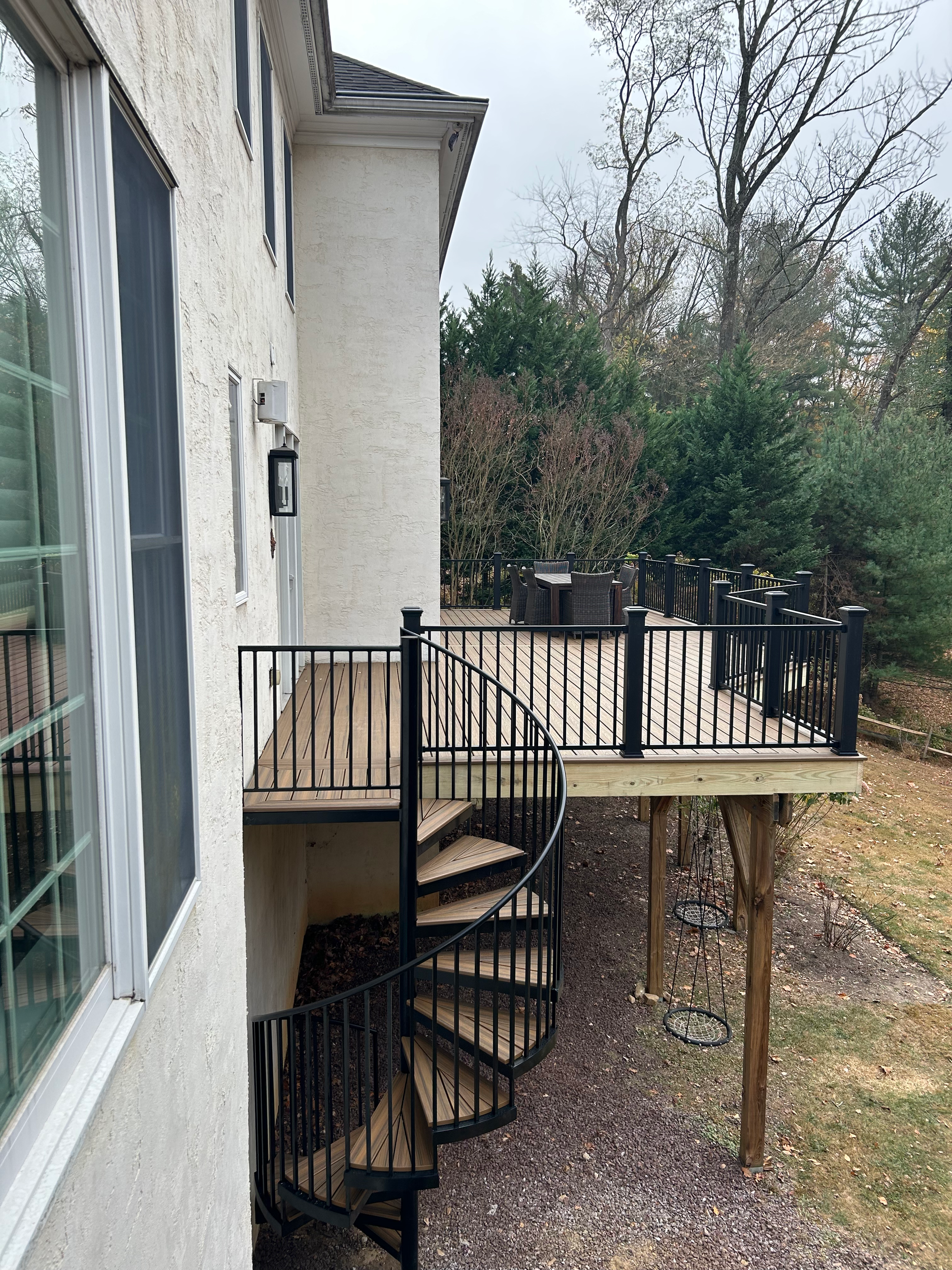 Spacious backyard deck with outdoor furniture, overlooking trees and yard, attached to a white house.