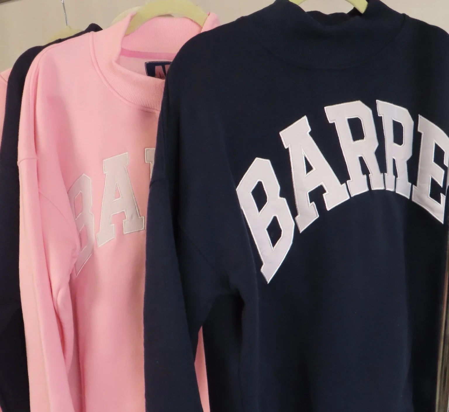 Pink and black sweatshirts hanging on a clothing rack, with the word 'PEACE' written on them.