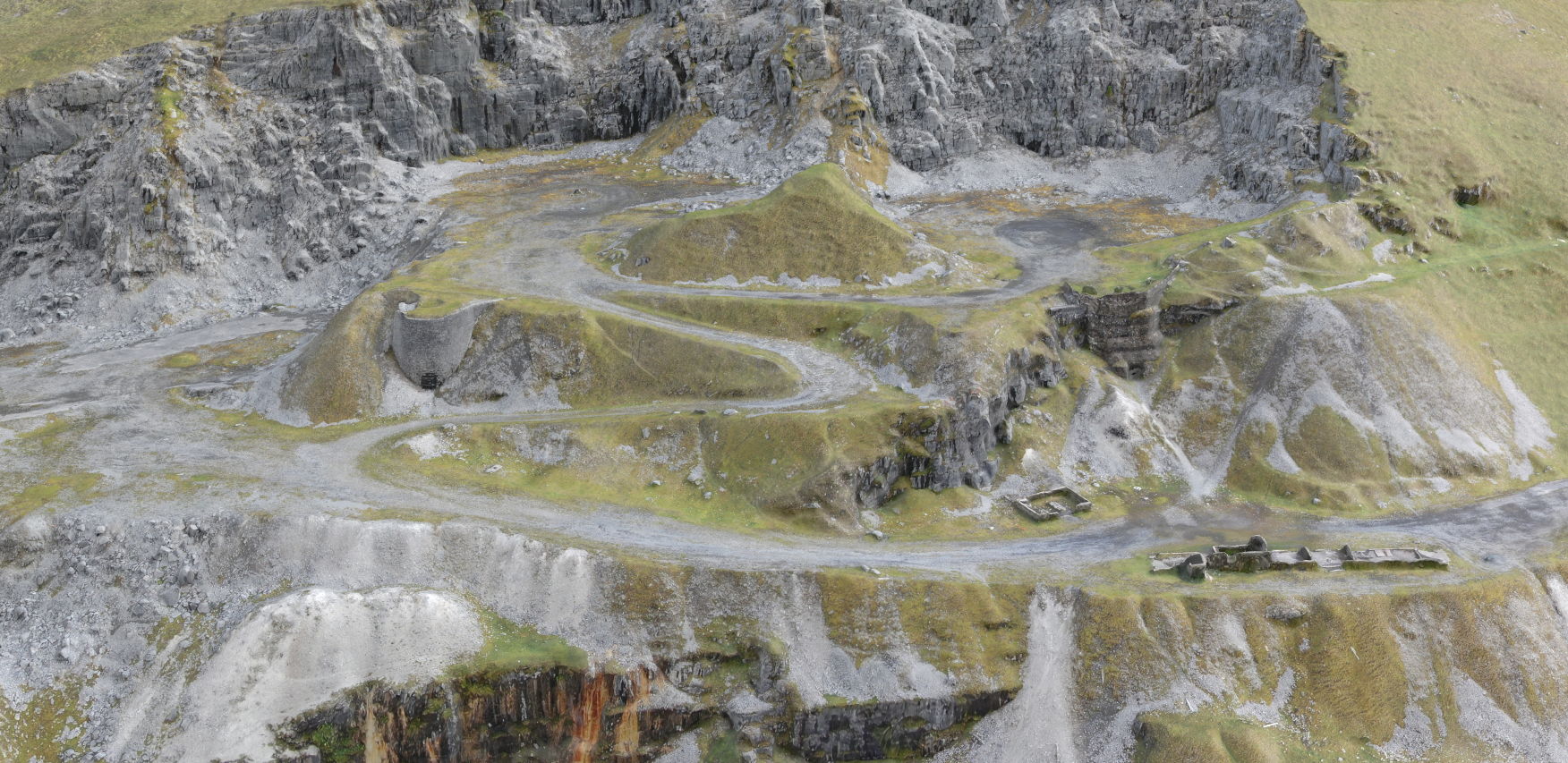 A mountainous landscape with a winding road, grassy hills, rocky cliffs, and ancient ruins.