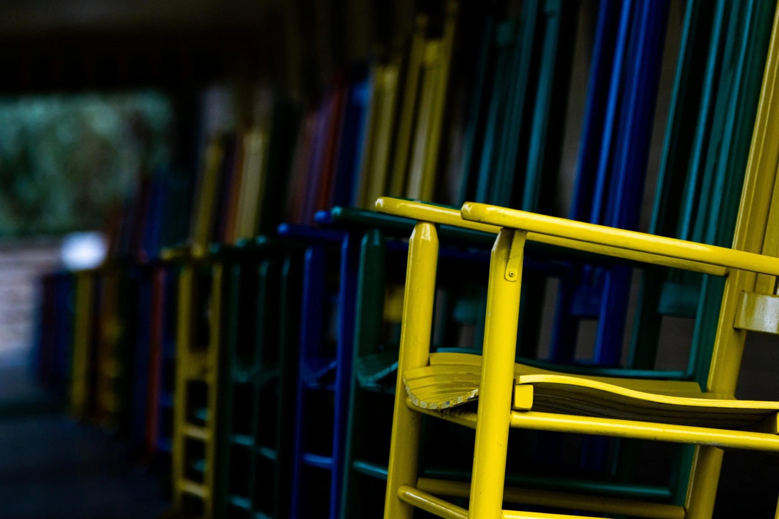 Colorful metal chairs stacked on each other in an outdoor setting.