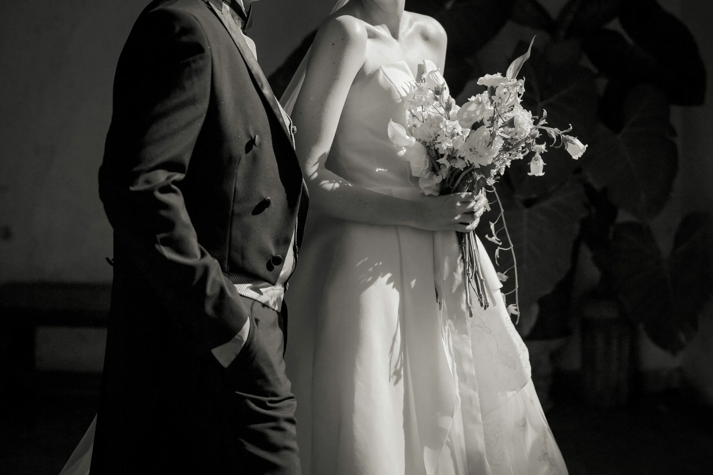 A person in a tuxedo standing next to a mannequin dressed in a wedding gown holding a bouquet of flowers.