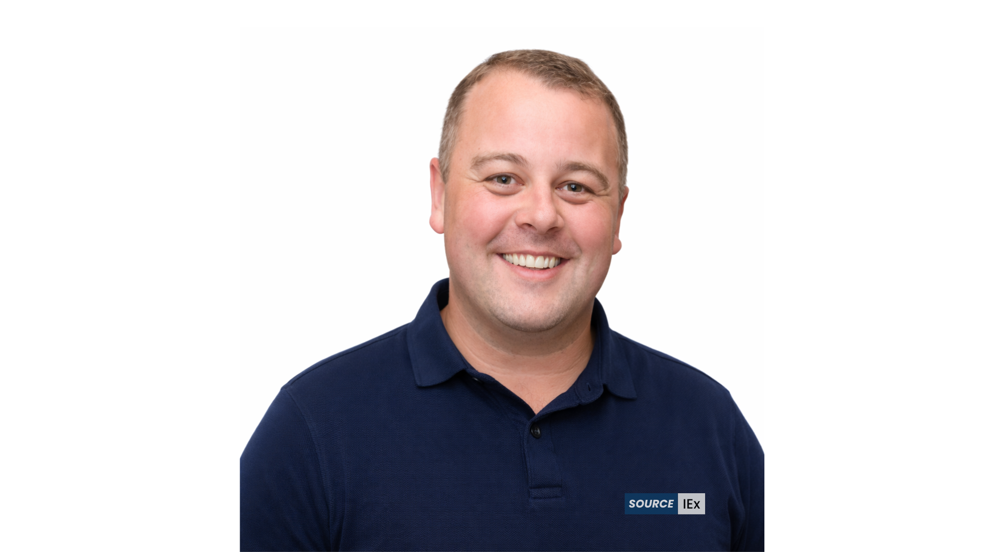 A smiling man with short Neo-Māori hair, wearing a navy blue polo shirt, against a white background.