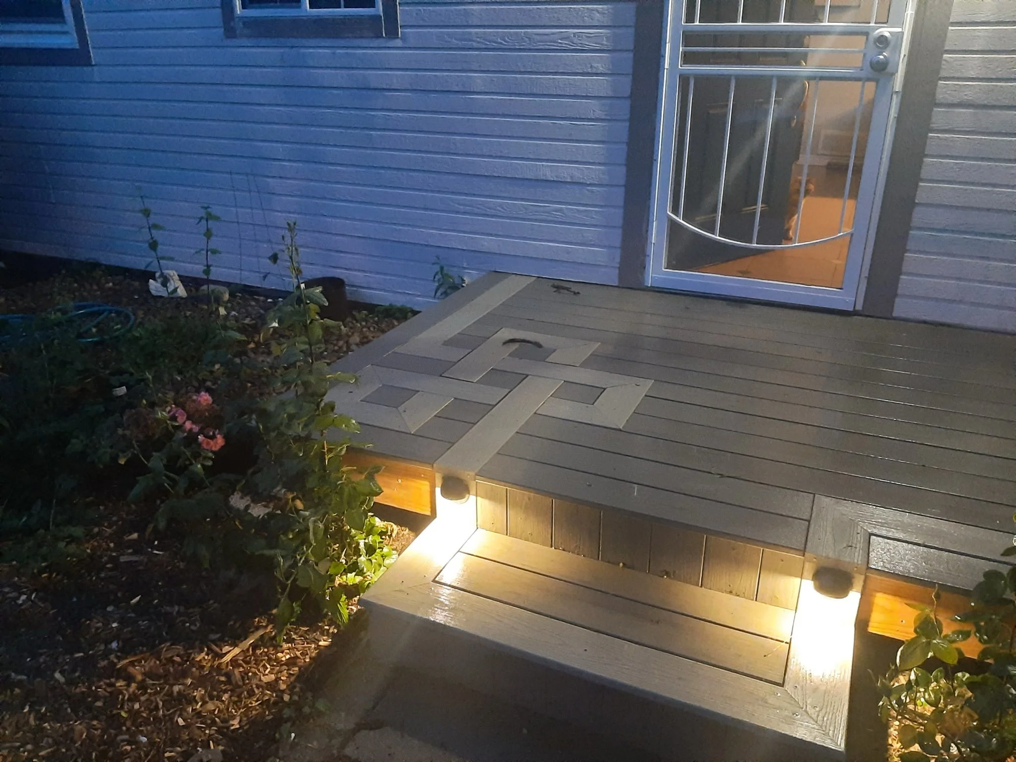 Front porch steps with celtic knot detail illuminated at night, leading to a glass door.