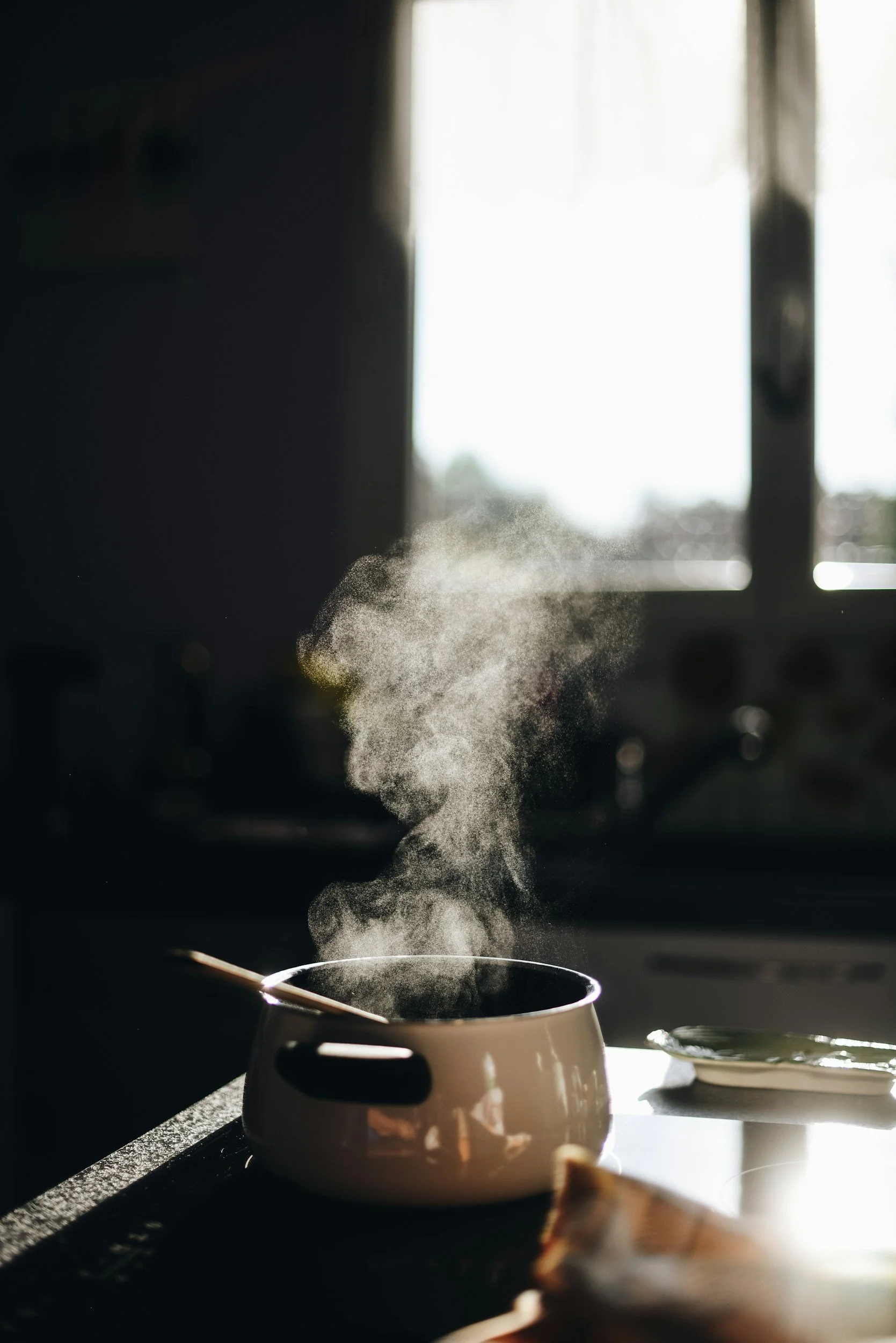 A steaming bowl on a kitchen counter with sunlight coming through a window in the background.