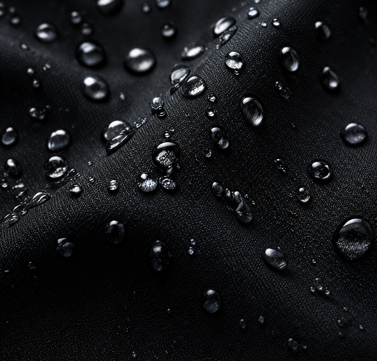 Close-up view of black fabric with water droplets on its surface.