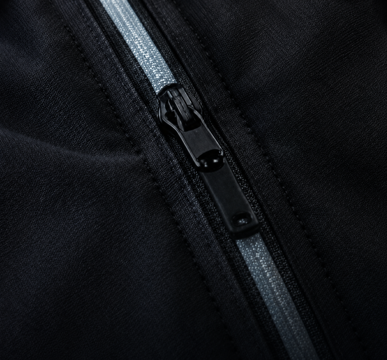 Close-up of a black zipper on a black fabric bag or clothing.