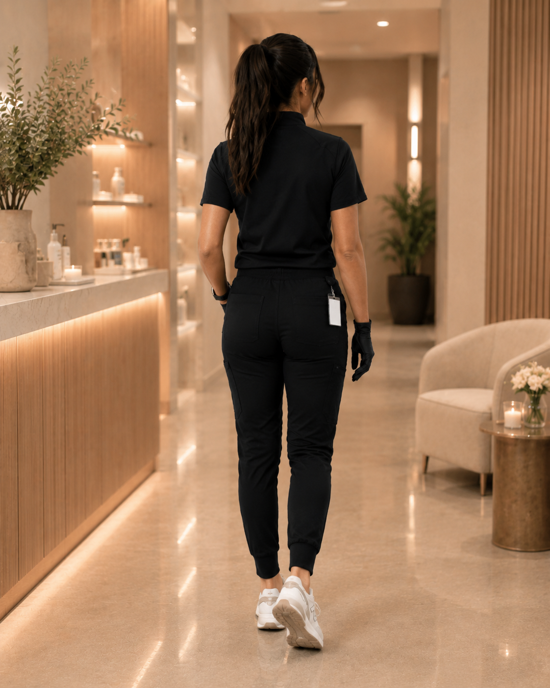 A woman dressed in black scrubs walking through a hotel lobby or reception area.