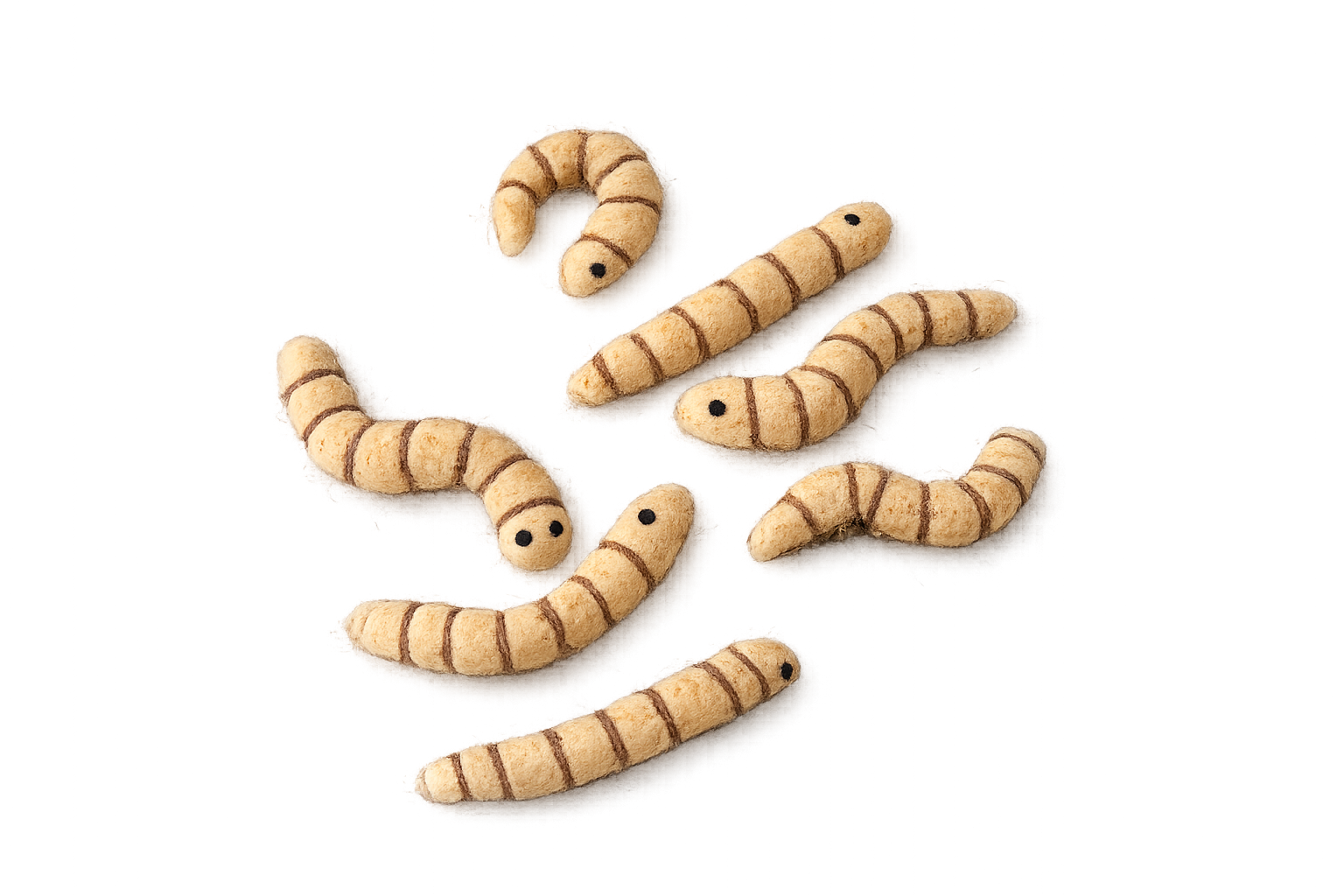 Close-up of plush toy worms with black eyes and brown stripes on a beige body scattered on a flat surface.