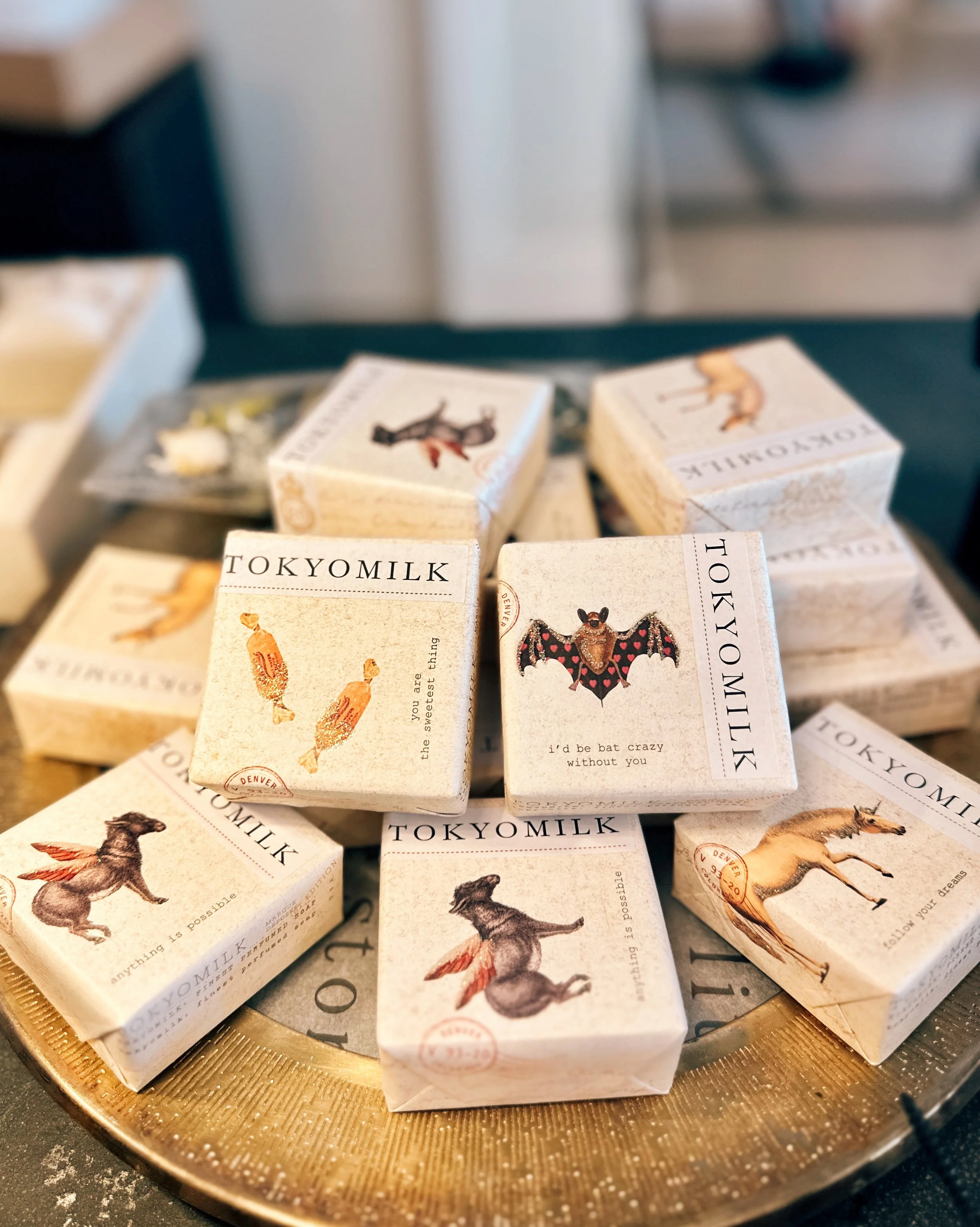 Display of several small toy milk cartons with illustrations of various animals and text on a gold-colored tray.