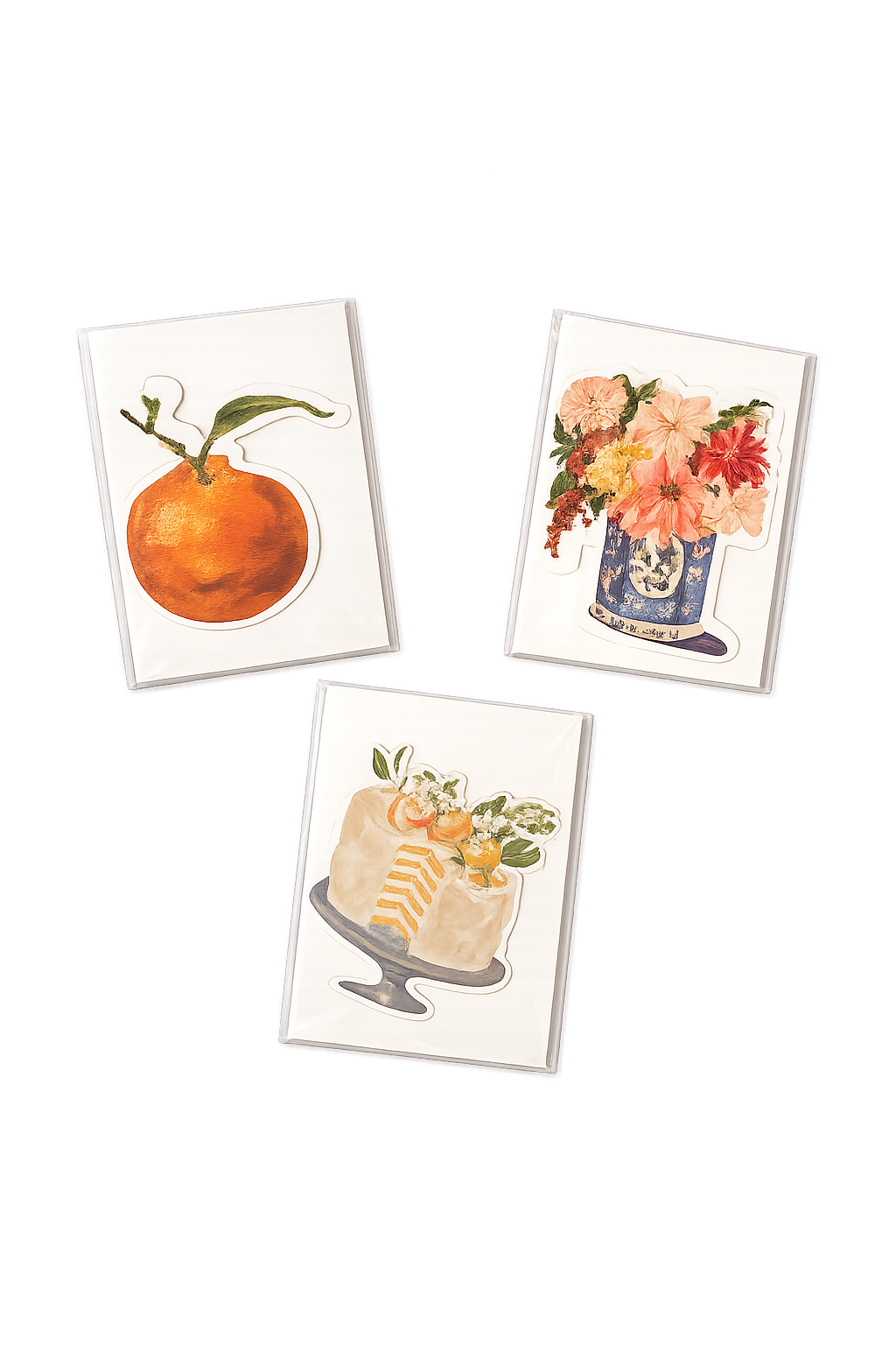 Three watercolor floral and fruit illustrations on display, including an orange with a leaf, a bouquet of pink and orange flowers in a vase, and a slice of layered cake with flowers on top.
