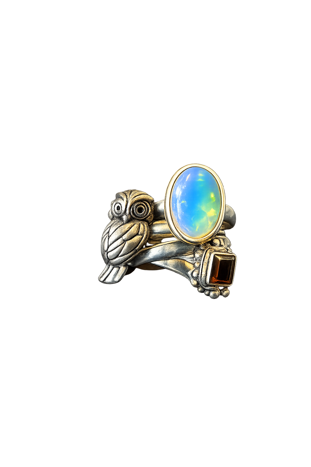 A decorative ring with a owl design featuring a large opalescent gemstone and a smaller rectangular gemstone, set against a dark, colorful light display background.