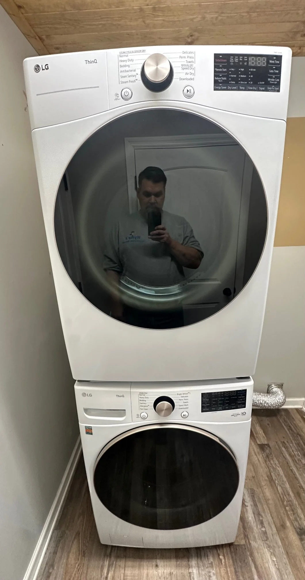 A front-loading washer and dryer stacked vertically in a laundry room, with their doors closed and controls visible on the front.