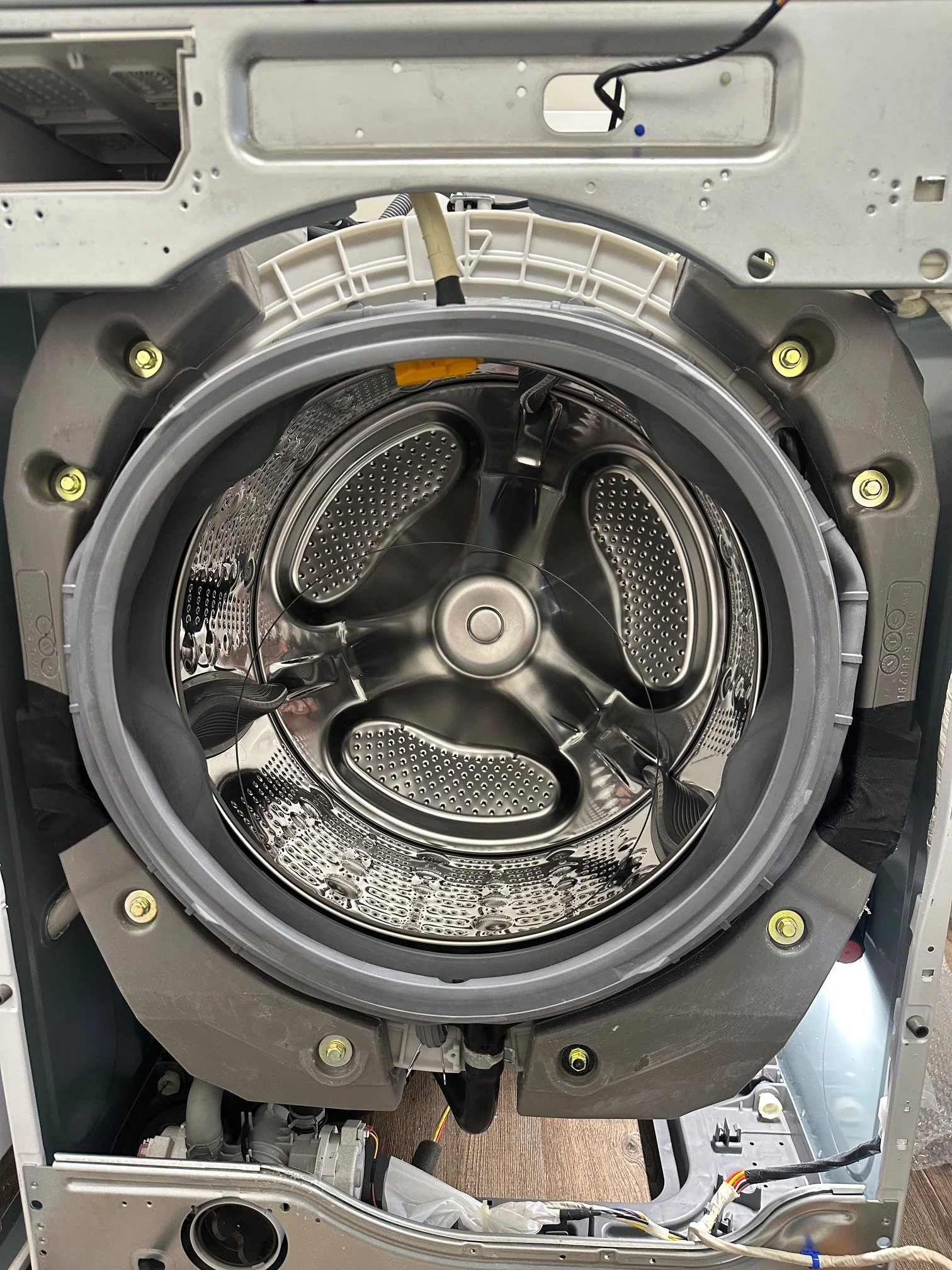 An open washing machine drum showing the metal interior and surrounding components.