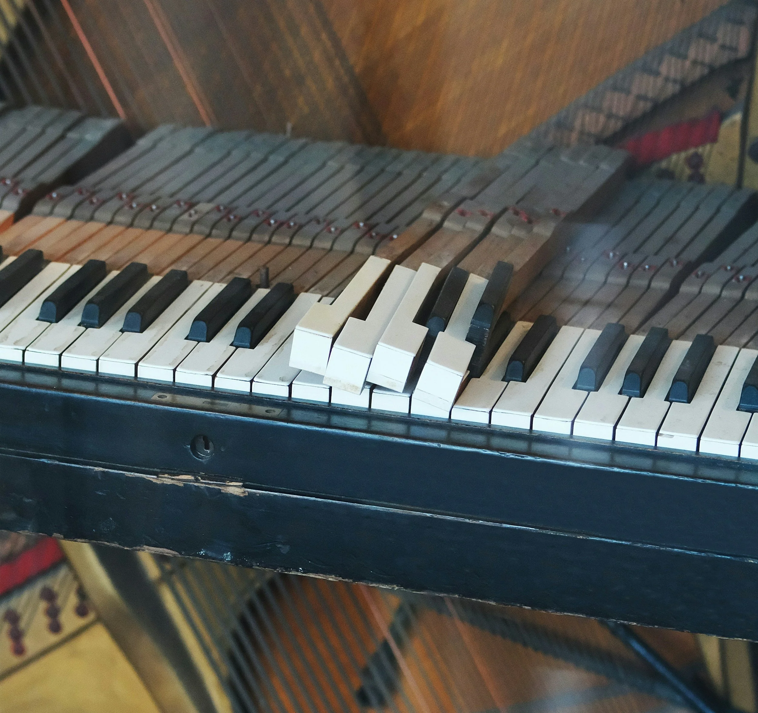 Close-up of a damaged piano keyboard with broken white keys and missing keys, showing aged and worn condition.