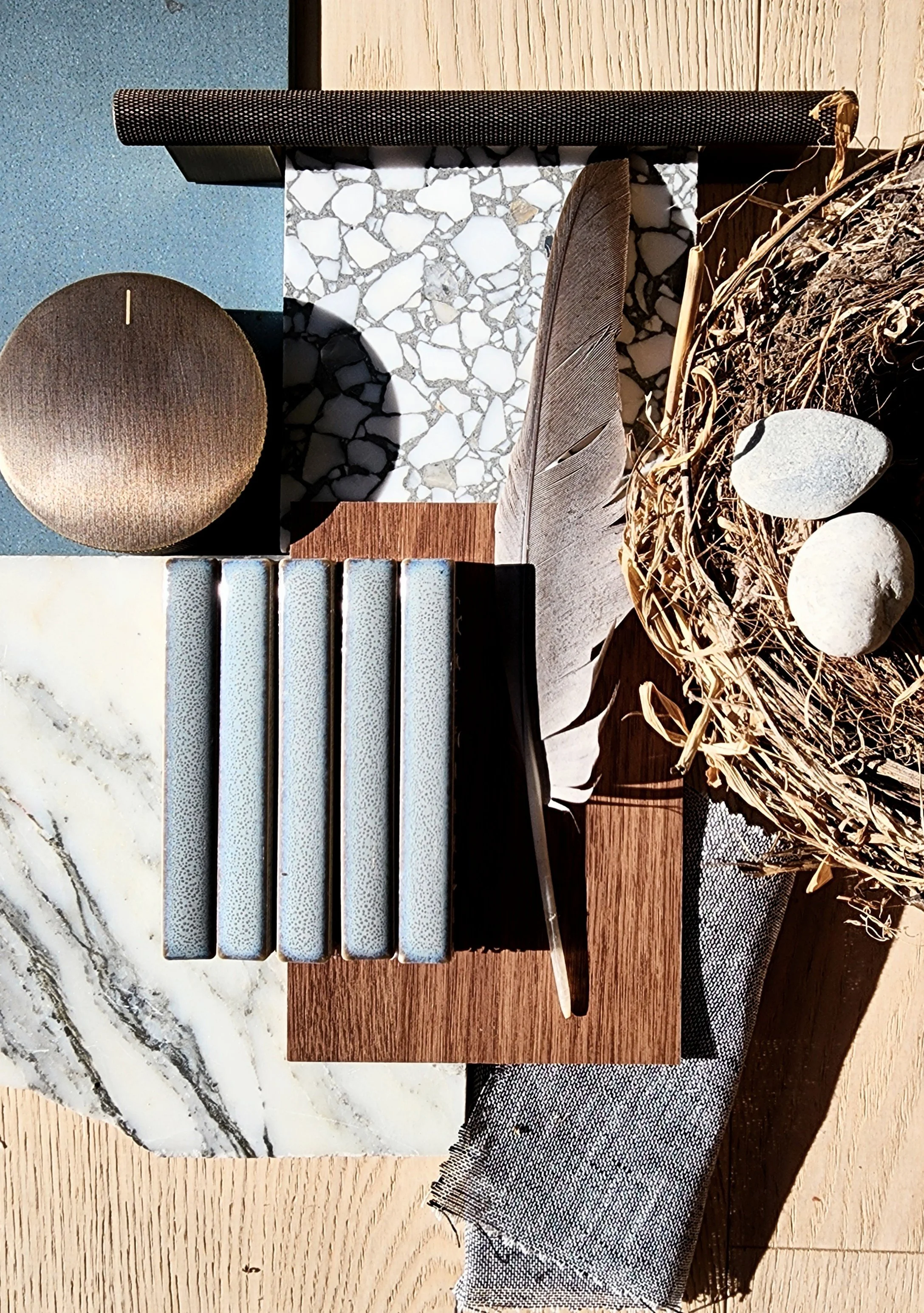 A collection of various material samples including tiles, wood, stone, fabric, and natural elements arranged on a table.