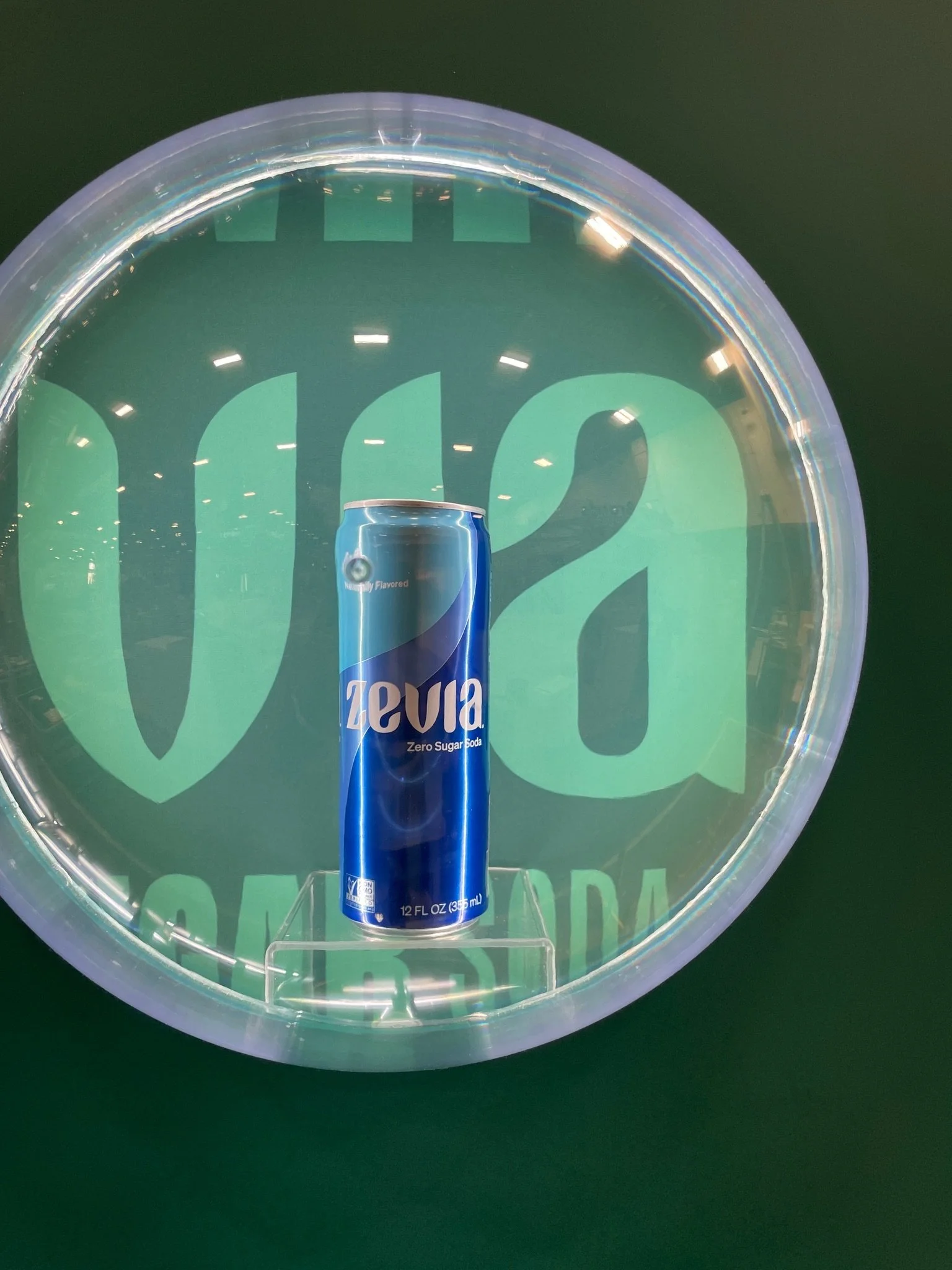 A blue zero sugar soda can inside a transparent display case with a green background and the words 'Welch's' in large green letters.