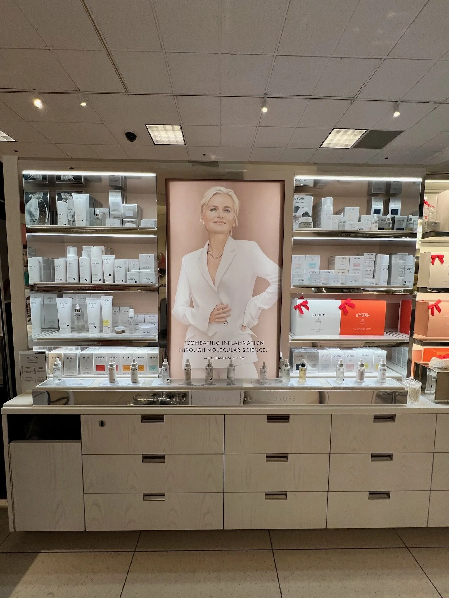 Display shelf with skincare products, a large poster of a woman, and reflective panels in a retail store.