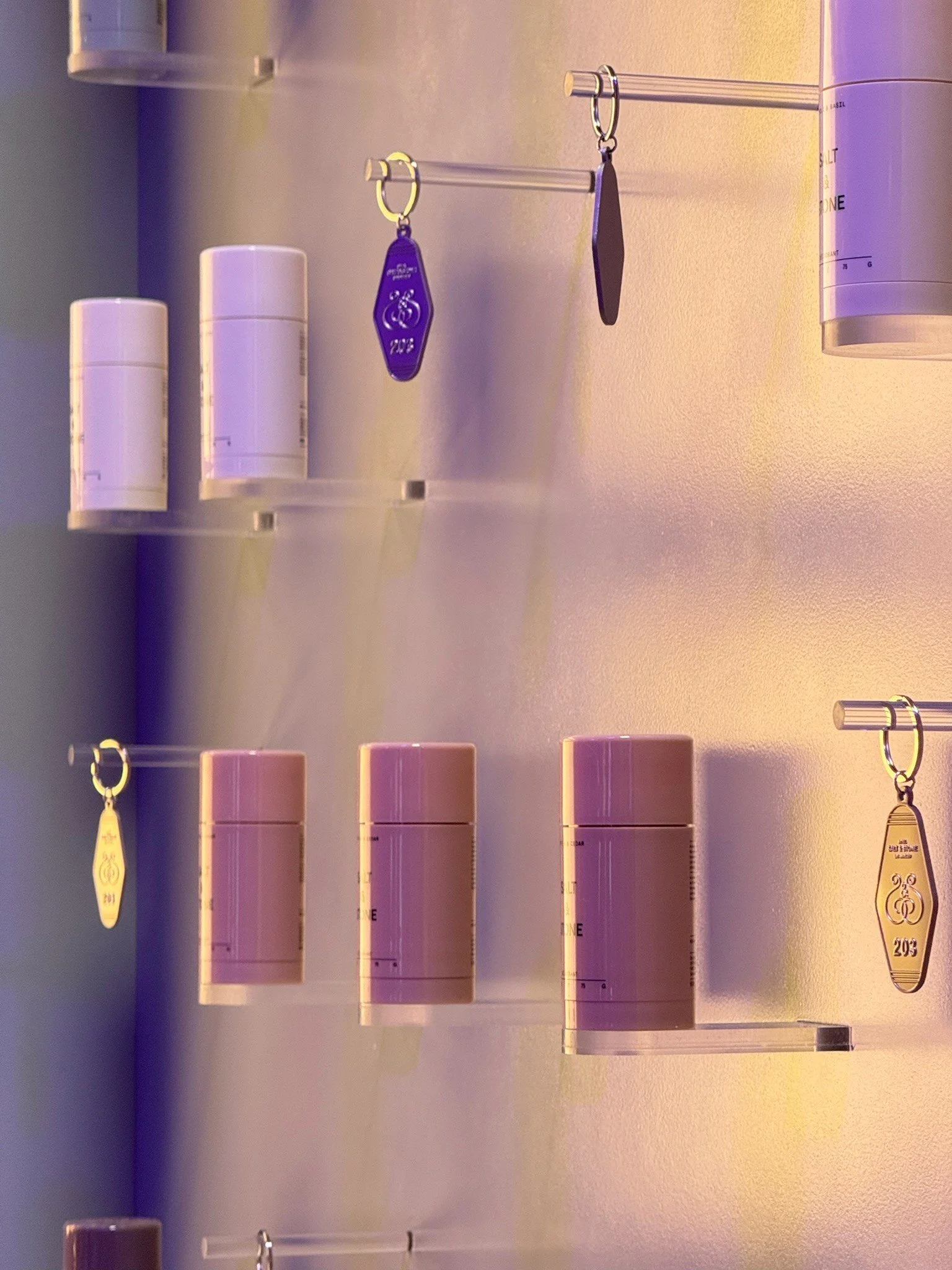 Multiple pills in pink, white, and purple bottles with medication labels on a wall-mounted storage unit, with unidentified keys hanging on a keyring.