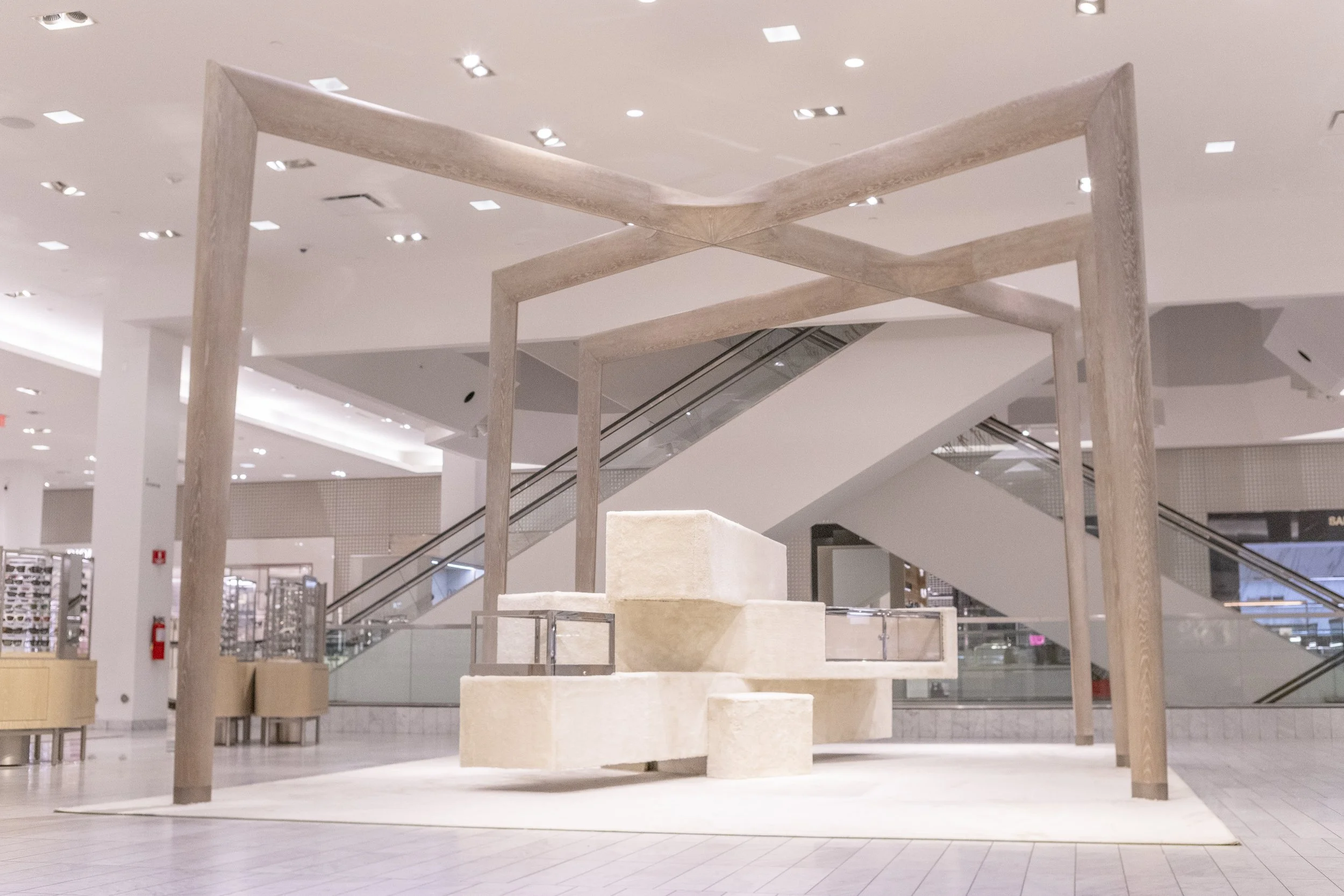 Interior display with a minimalist wooden structure and steps in a shopping mall.
