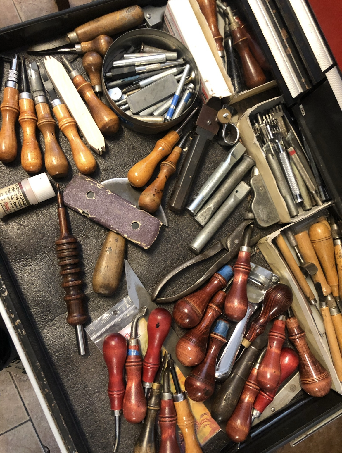 A collection of hand tools, including chisels, screwdrivers, and other woodworking or carpentry tools, scattered on a black surface.