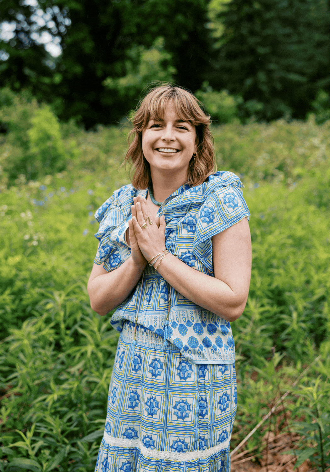 Photo of laura smiling outdoors in a floral blue dress with hands pressed together, followed by a portrait where she is looking up at a large tree