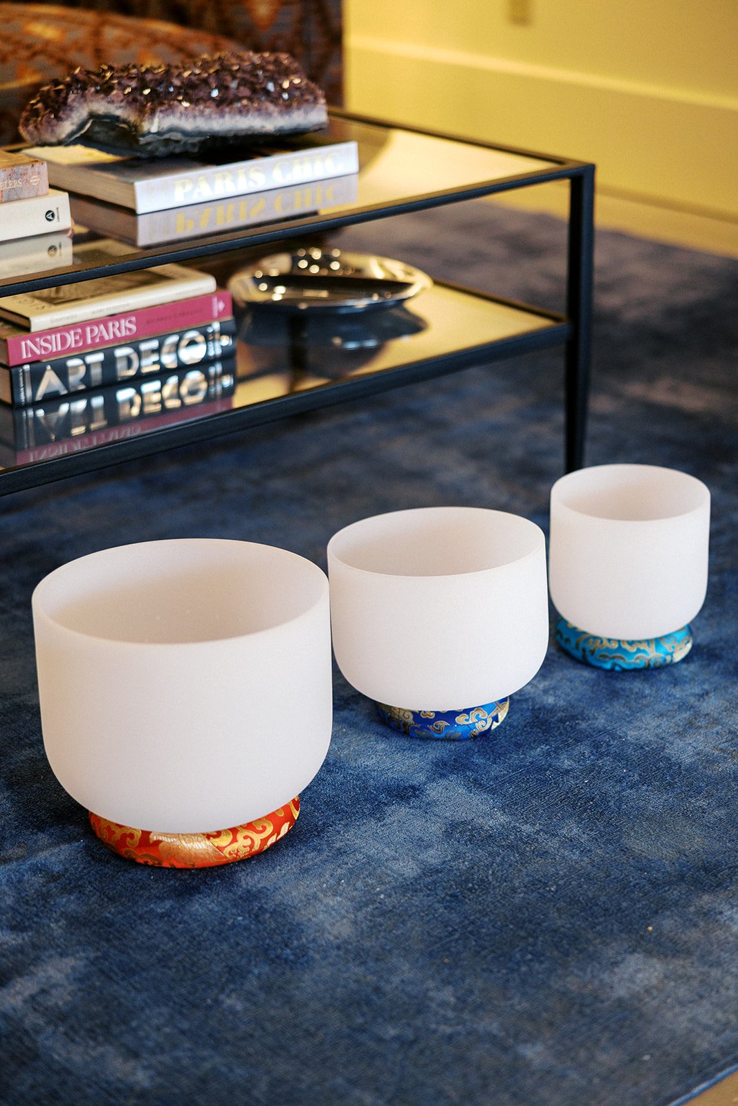 3 different sizes of singing bowls displayed in calm and warm therapy office in front of coffee table with books and decor