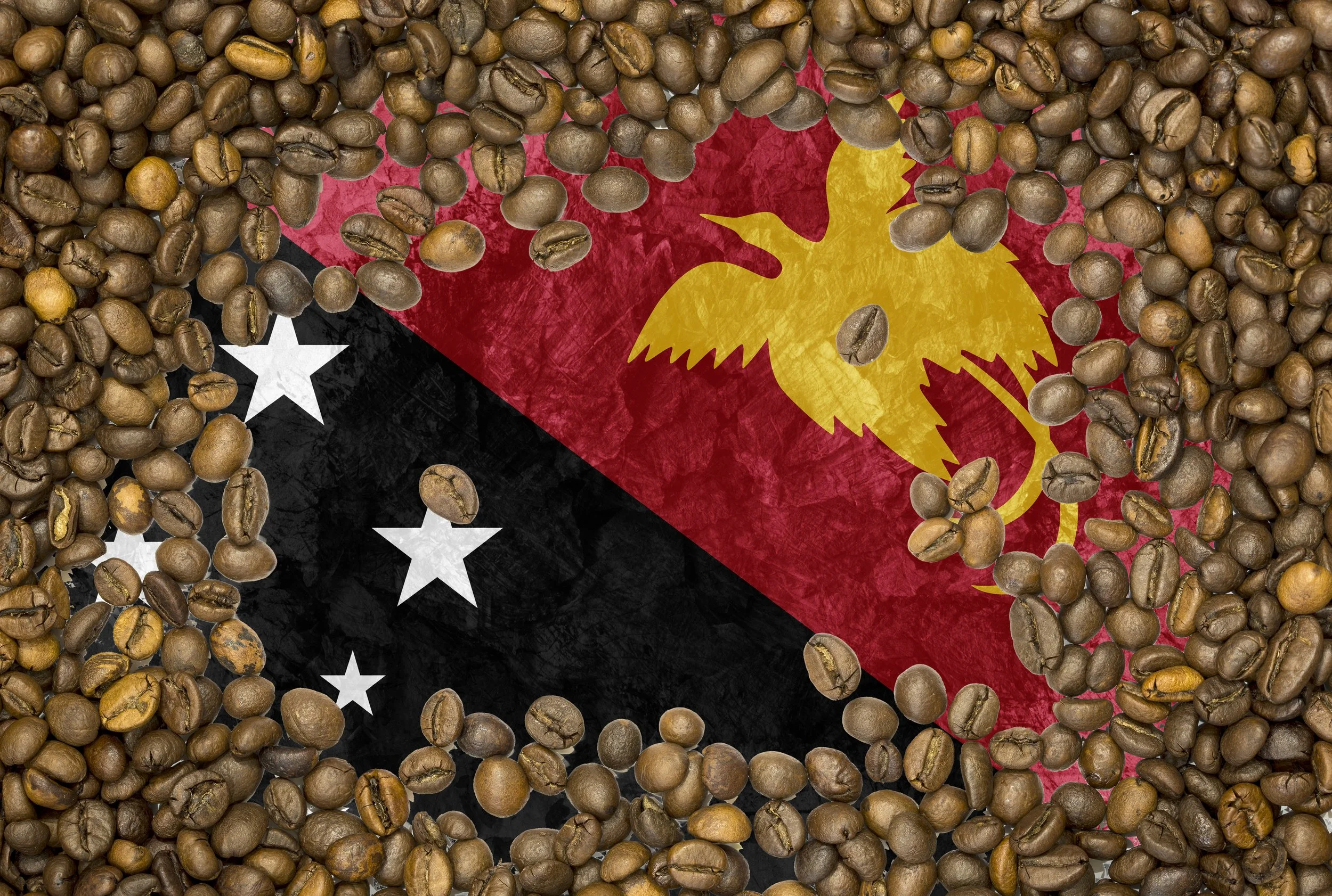 Roasted coffee beans spread over a Papua New Guinea flag.