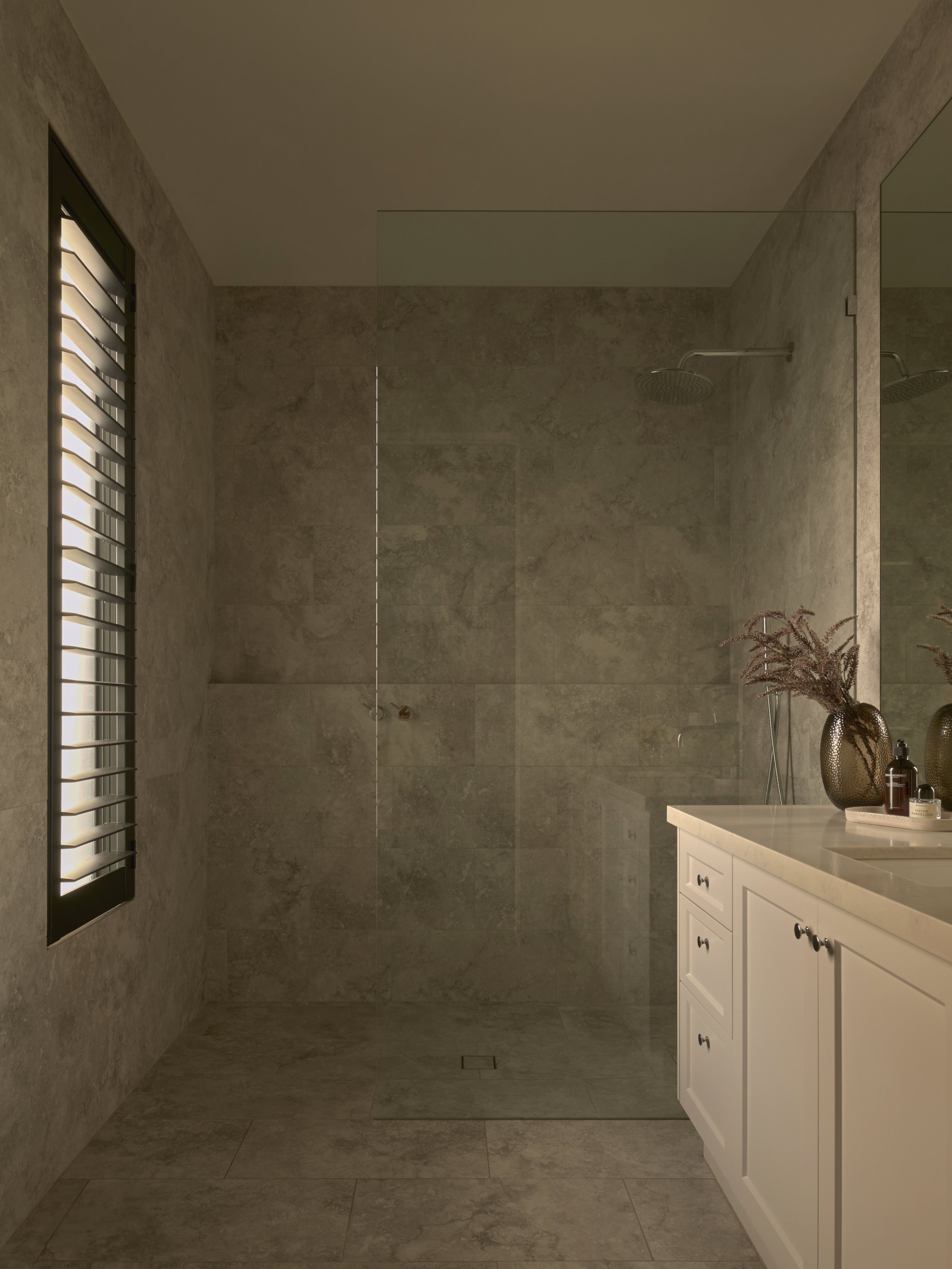 Modern bathroom with a walk-in shower and a white vanity with decorative vases and bottles.