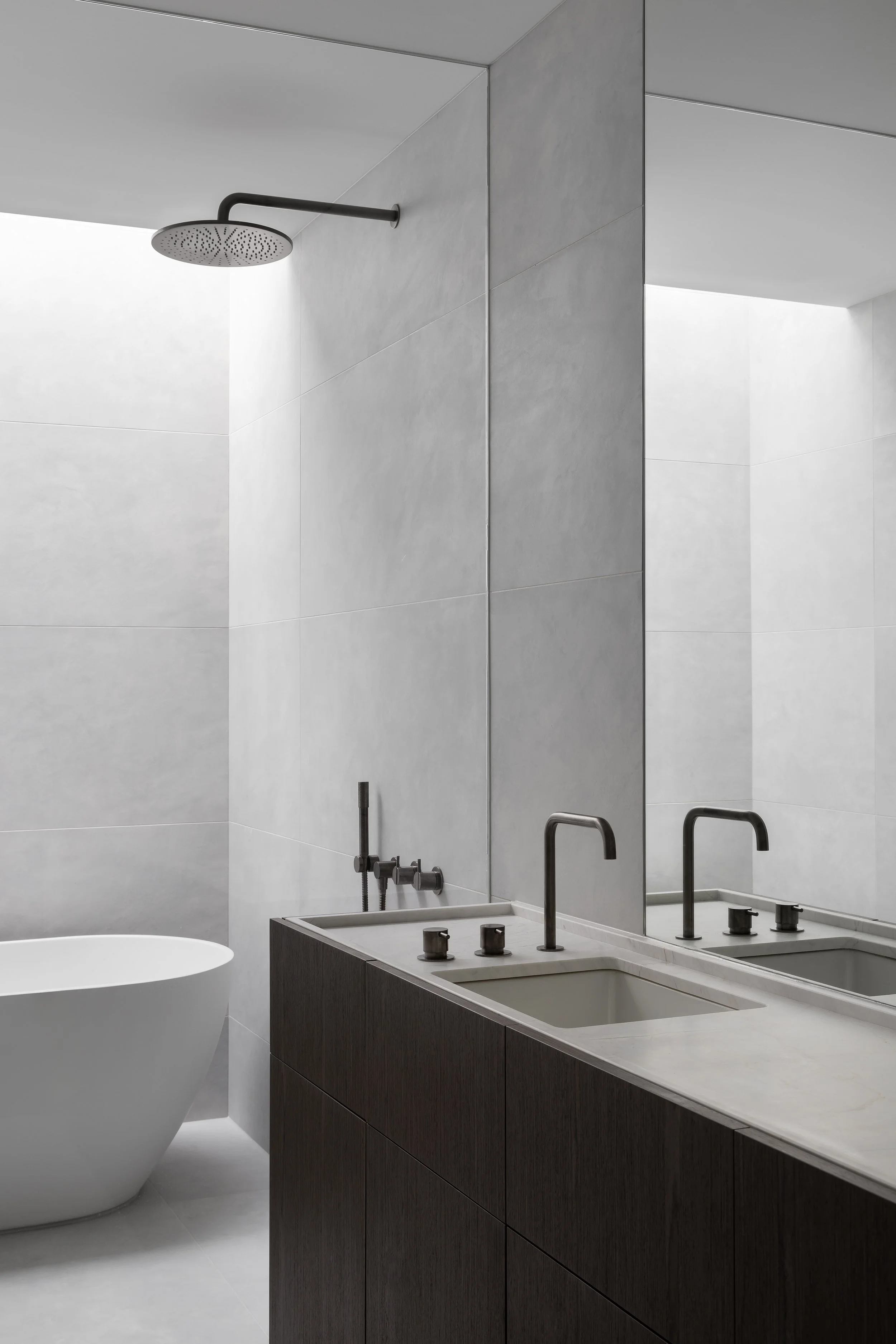 Modern bathroom with a shower head, double sink vanity with black fixtures, large mirror, and a freestanding bathtub.