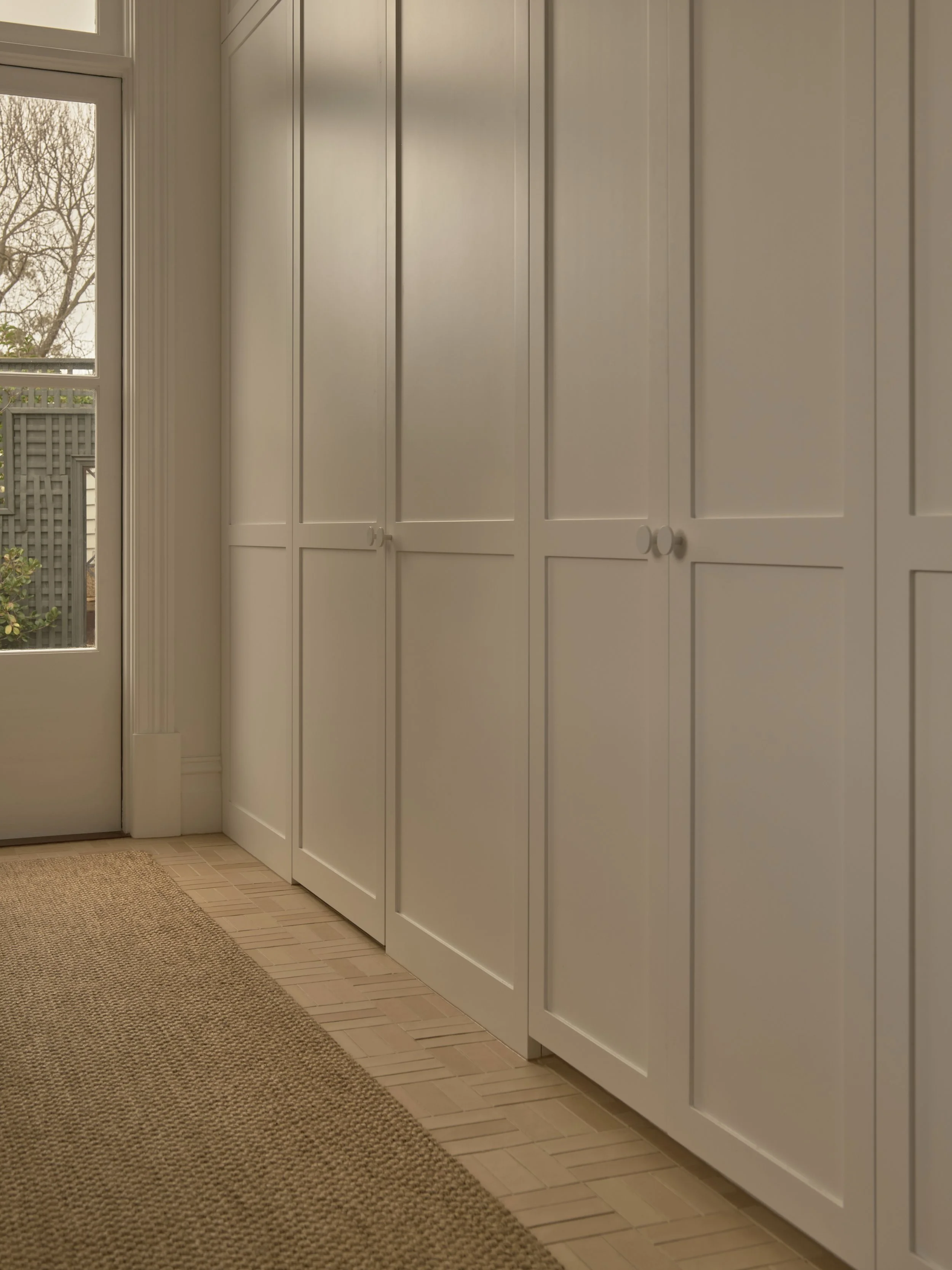 A room with white cabinets and a window showing trees outside.