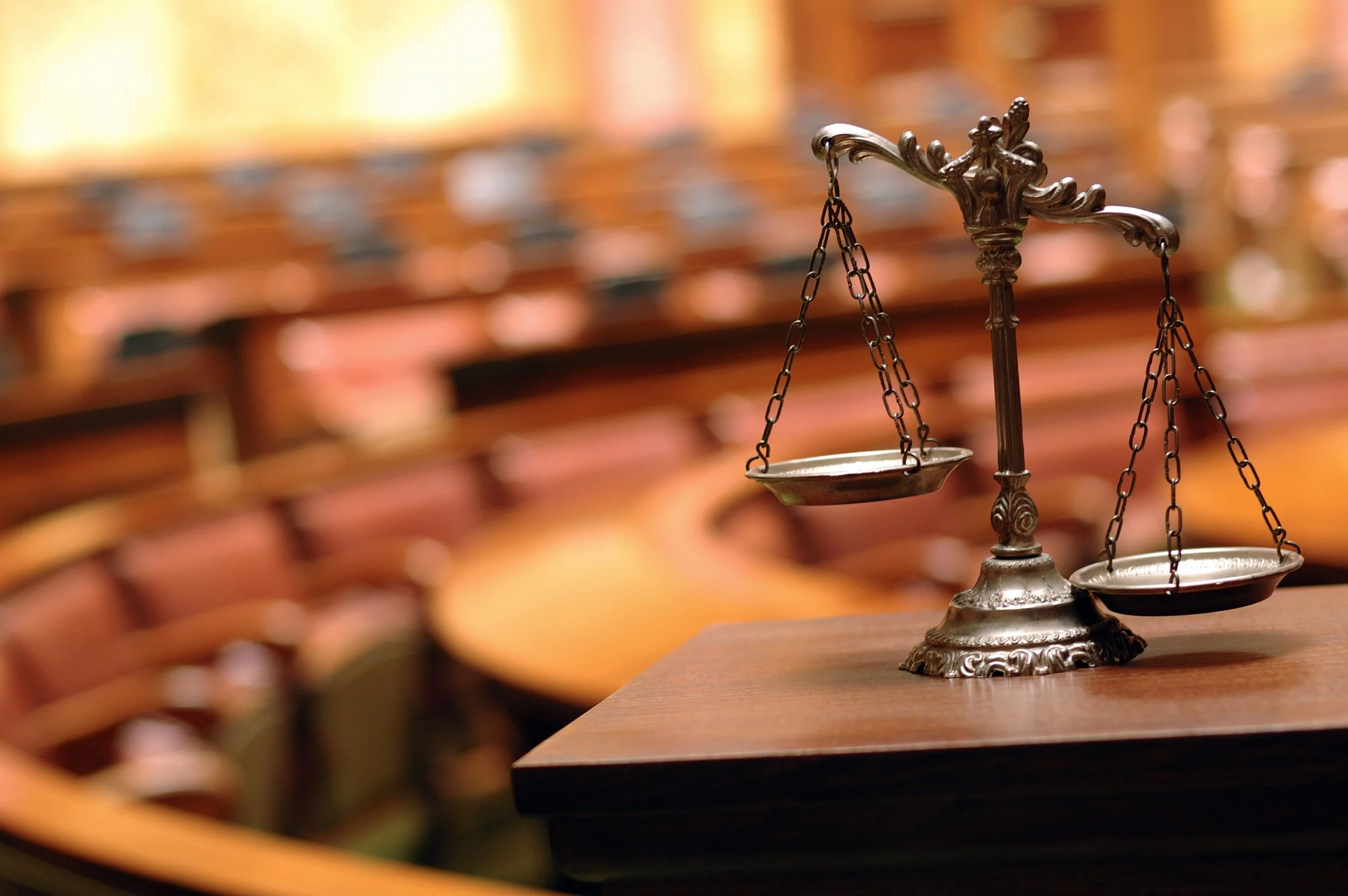 Scales of Justice inside a wooden courtroom setting