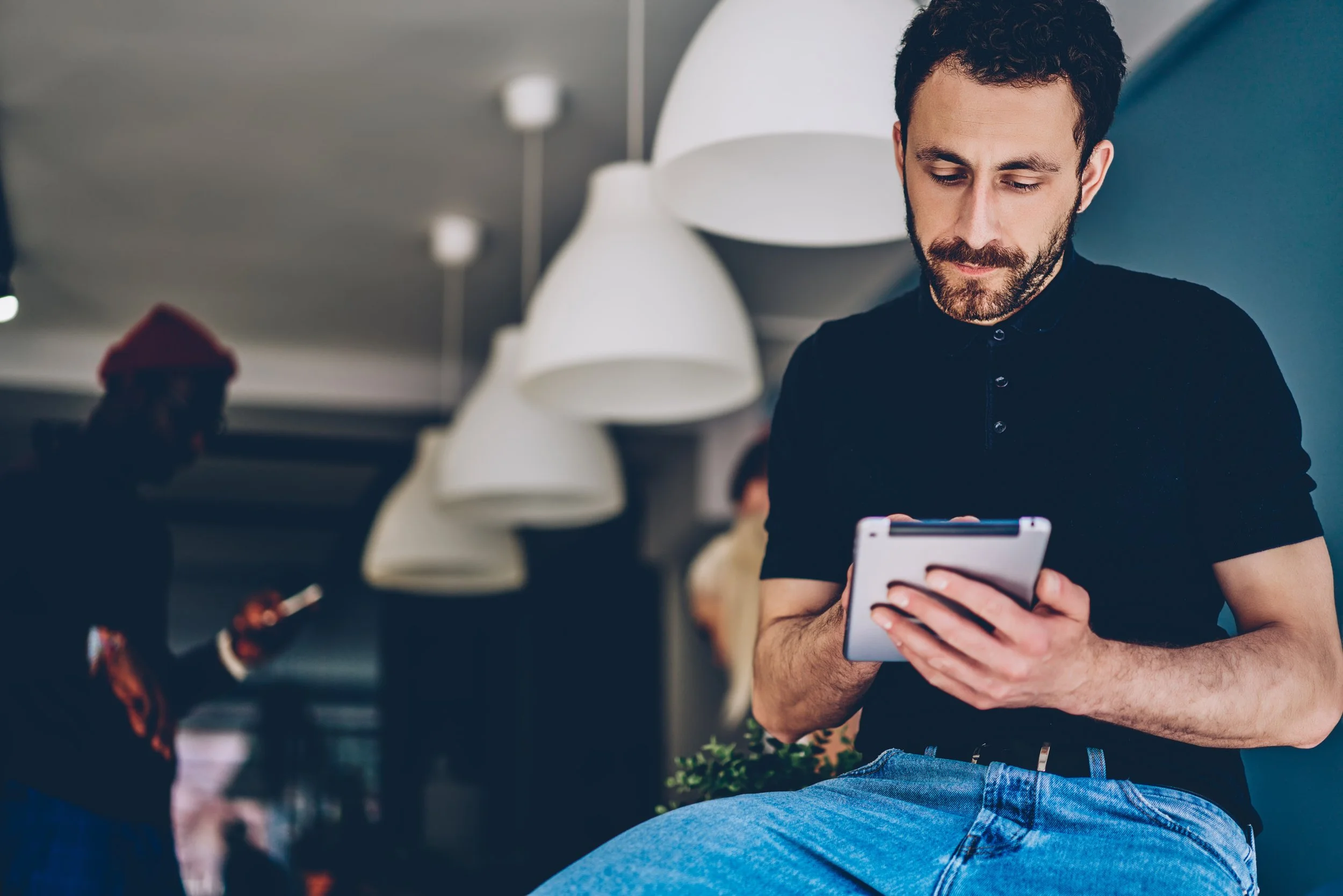 Man leaning on table while using a tablet