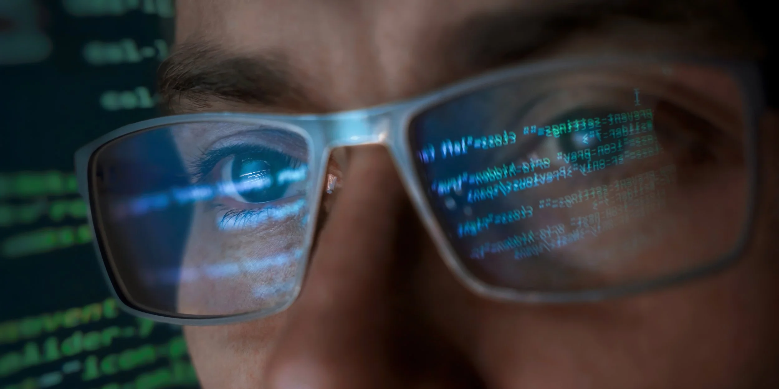 Closeup of face with glasses that are reflecting text or code