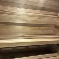 A wooden sauna interior with horizontal wooden panels and a bench.
