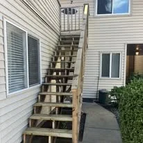 Wooden staircase outside a house, leading to a second-floor door.