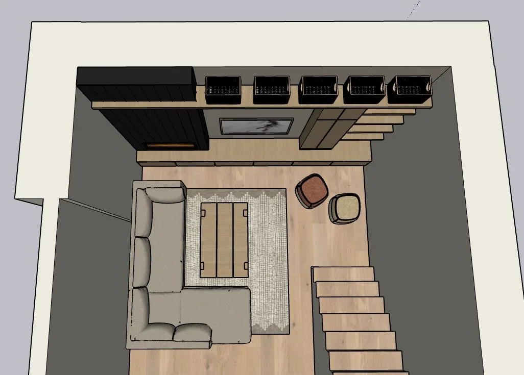 Top-down view of a living room with a beige L-shaped sofa, a patterned area rug, a wooden coffee table, two small stools, a wall-mounted TV, and surrounding shelving and décor.