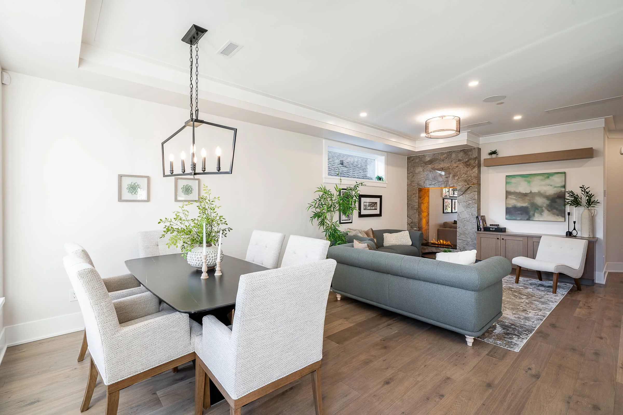 Open-concept living and dining area with modern furniture, fireplace, and decorative accents.