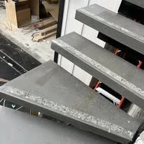 Concrete stairs with three steps leading up, partially under construction or renovation.