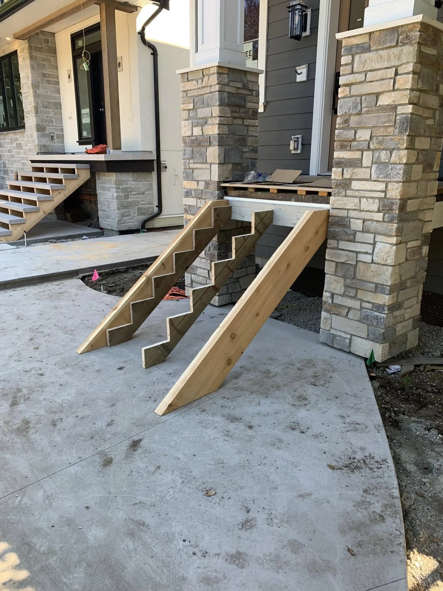 Wooden stairs and supports being constructed at the entrance of a house.