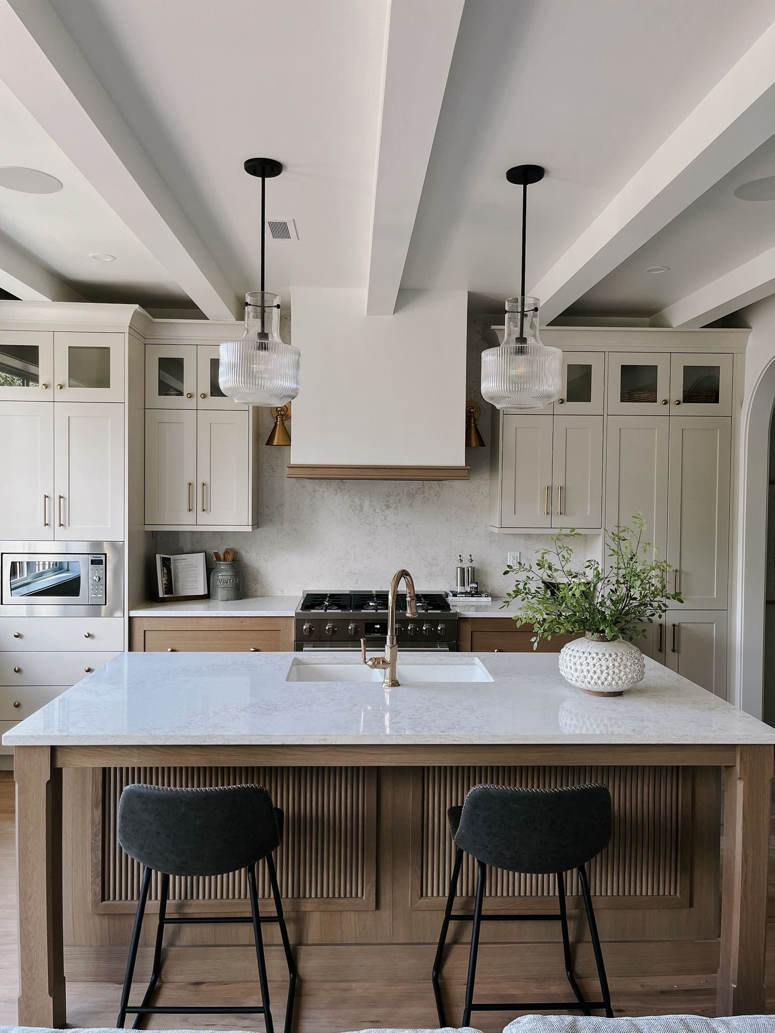 Modern kitchen with a large white marble island, pendant lighting, and white cabinetry.