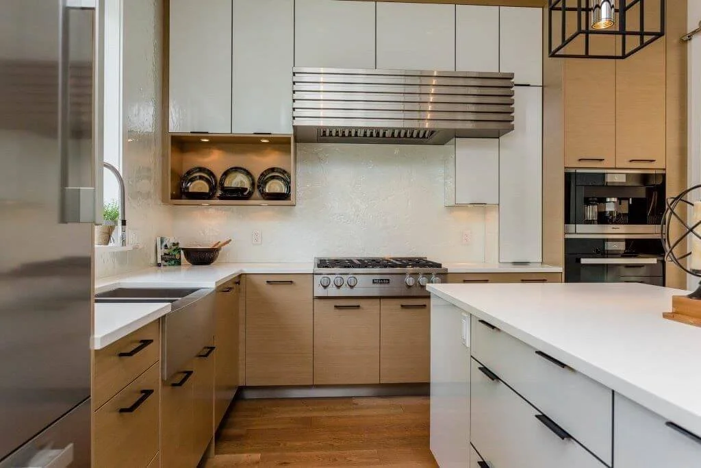 Modern kitchen with beige cabinets, white countertops, stainless steel appliances, and a black light fixture.