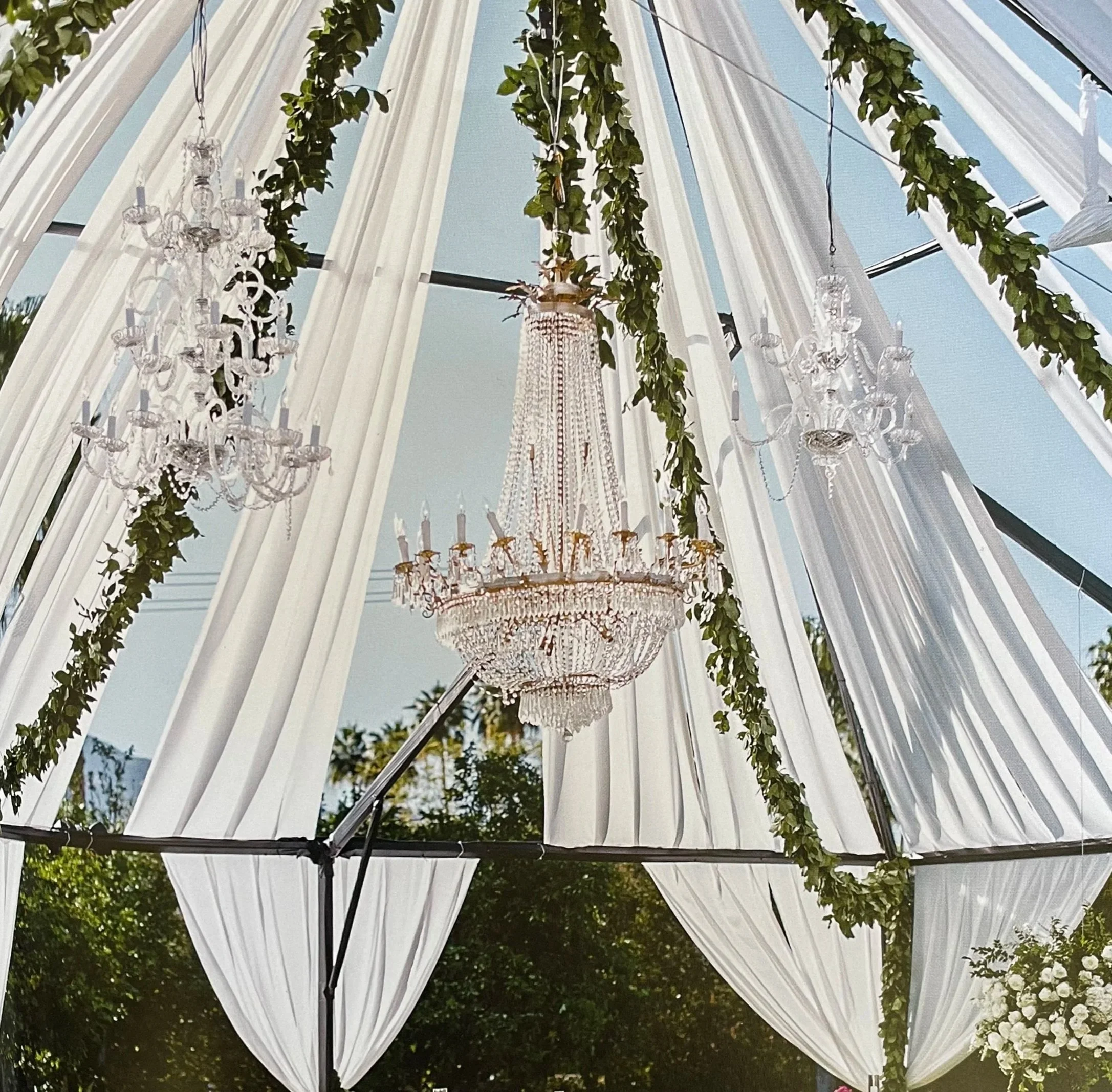 Wedding reception chandelier hanging with eucalyptus garland and sheer drapes