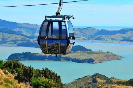 A gondola lift hanging over a landscape with lakes and hills.
