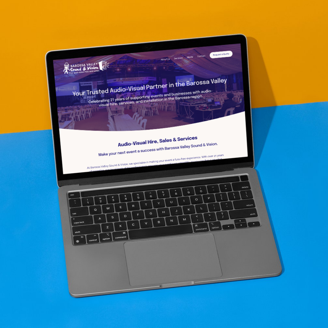 A laptop displaying a website for Barossa Valley Sound & Vision, a company specializing in audio-visual services, set against a colorful background with yellow, blue, and orange sections.