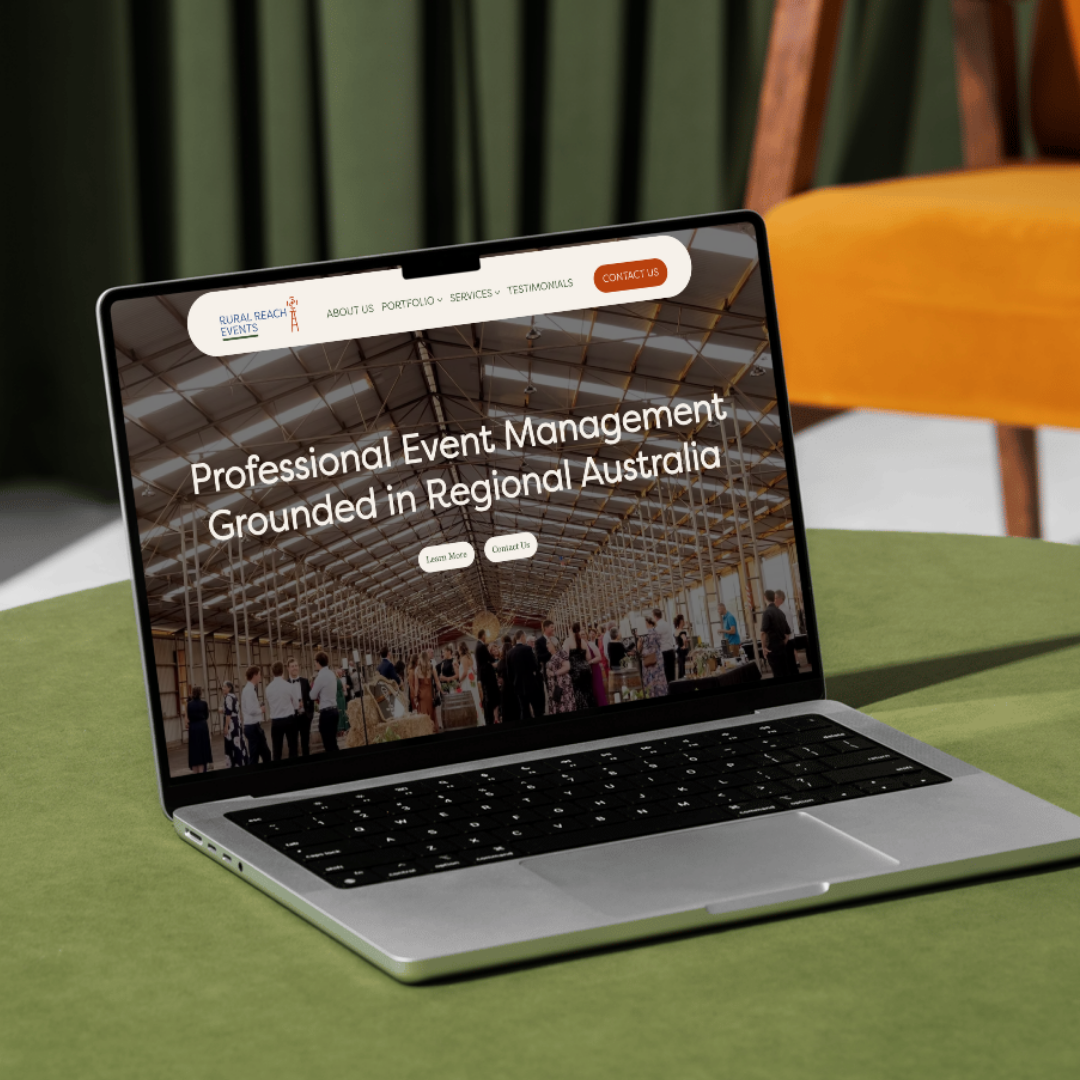 Laptop on a green table displaying a website for event management in Australia, with a large indoor event space shown on the screen